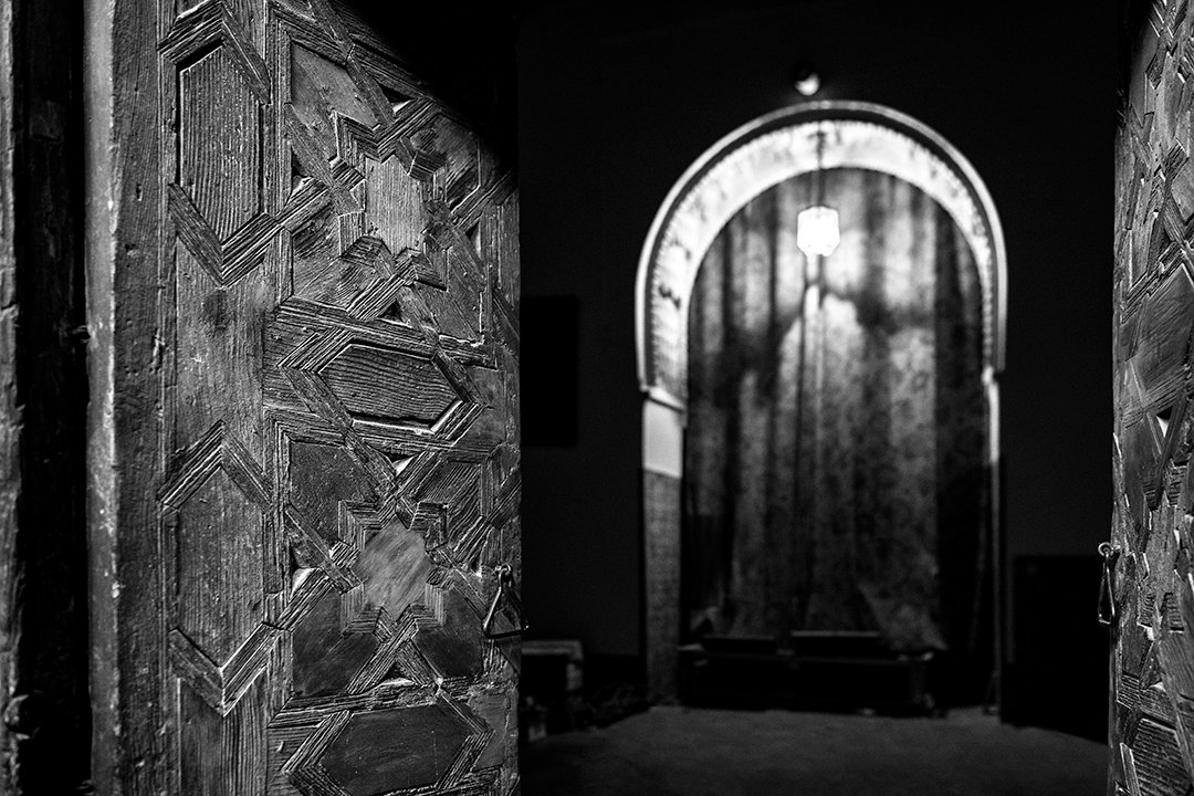 A dark corridor with arches and a curtain at the far end.